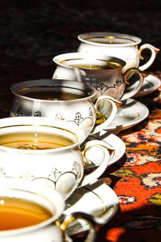 vintage soviet porcelain cups of tea with saucers on turkish carpet, traditional tea ceremony, sunlight
