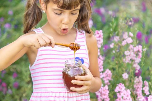 Child eats honey summer photo. Selective focus.