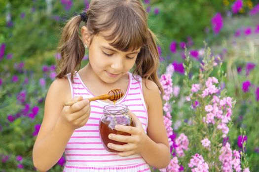 Child eats honey summer photo. Selective focus.
