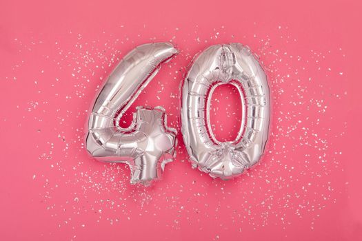 Silver balloon in shape of number fourty 40 pink background
