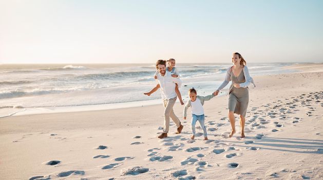 Happy family walking on the beach together. Young caucasian family relaxing together on the beach. Parents bonding with their children by the ocean. Mother and father walking with their children