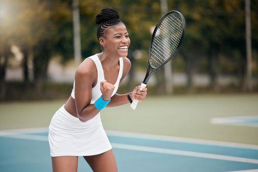 Excited tennis player cheering during a match. Cheerful tennis player celebrating her success after a game. Young african american athlete playing a game of tennis. Girl playing tennis