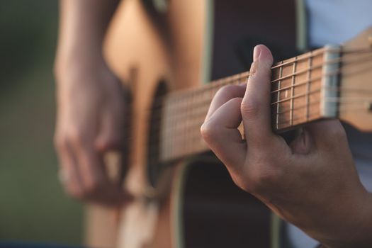 Woman's hands playing acoustic guitar. Musical instrument for recreation or hobby passion concept. Close up of hands playing acoustic guitar