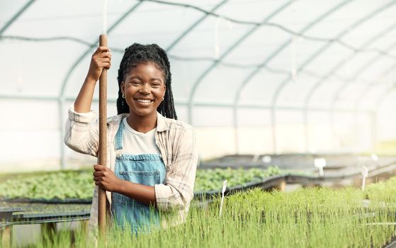 Portrait of a happy woman working on a farm. Smiling farmer working in a greenhouse. African american woman working on a farm. Young woman cultivating agriculture on a sustainable farm