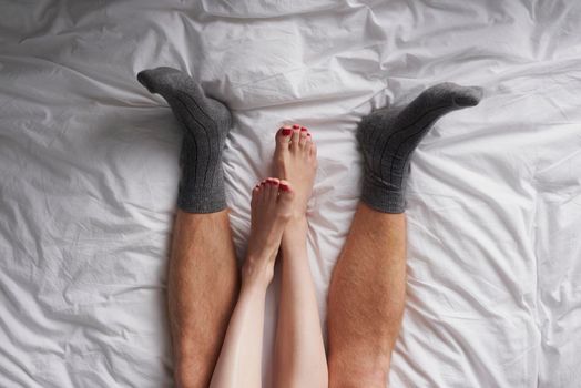 Closeup of the legs of a couple lying in bed affectionately cuddling. Closeup of the legs of a couple lying in bed affectionately cuddling.