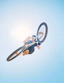 Man showing his cycling skills while out cycling on a bicycle outside. Adrenaline junkie practicing a dirt jump outdoors. Male wearing a helmet doing tricks with a bike. Hovering, passionate and free
