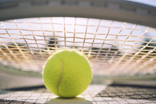 Closeup view of a tennis ball and tennis racket on a court in a sports club during the day. Playing tennis is exercise, promotes health, wellness and fitness. Macro view of tennis gear and equipment