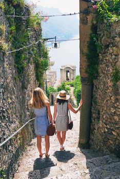 Two friends looking at view of ocean. Girlfriends travelling in Italy on summer beach vacation exploring to discover carefree lifestyle