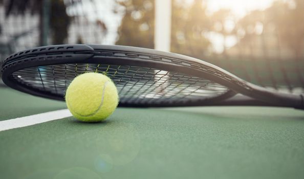 Closeup view of a tennis ball and tennis racket on a court in a sports club during the day. Playing tennis is exercise, promotes health, wellness and fitness. Macro view of tennis gear and equipment