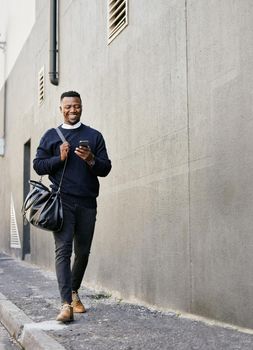 Businessman using his cellphone while walking in the city. Man using cellphone while commuting to work. Using internet while walking outside. Man using internet while commuting