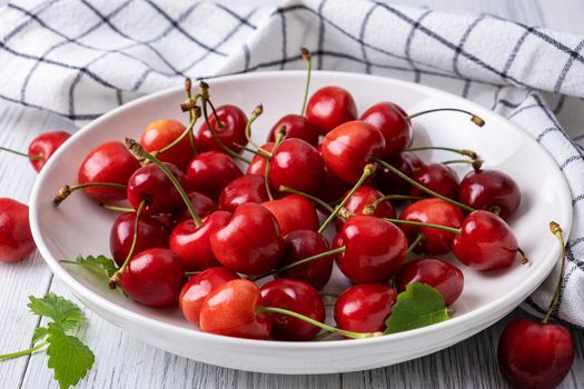 Ripe juicy sweet cherries lie on a white porcelain plate