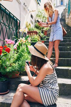 Two friends taking photos of pot flowers using smartphone for social media while on adventure travel vacation
