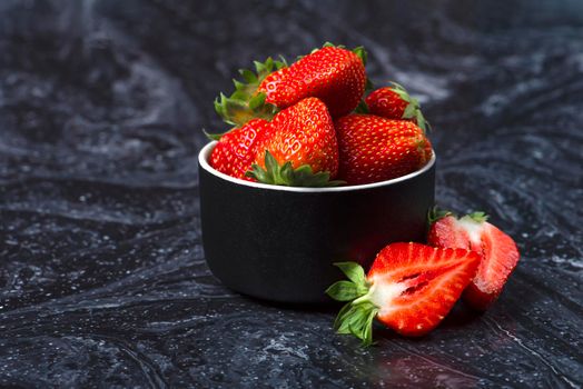 Strawberries on black marble. Ripe strawberries in a saucer on a black background. Place to insert text