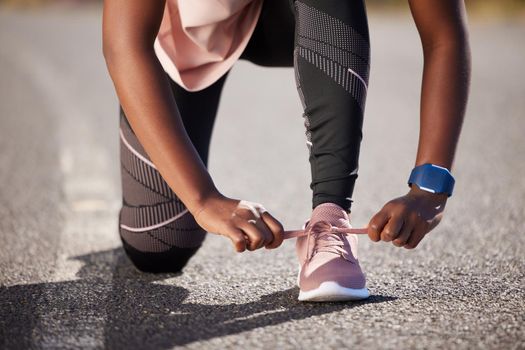 Active and fit woman tying the laces of her sneakers for exercise outdoors. Athlete fastening her shoes to get ready for a run or jog in the morning. Preparing for a refreshing cardio workout outside