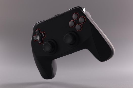 Black game joystick with buttons on gray background