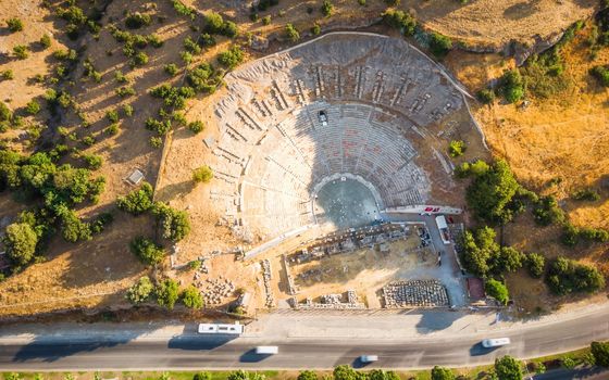 Top Aerial view of historical places, theater ruins, massive ancient theatre of Halicarnassus with highway crossing town Bodrum, Turkey