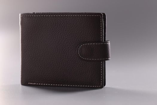 Brown leather closed wallet on gray background
