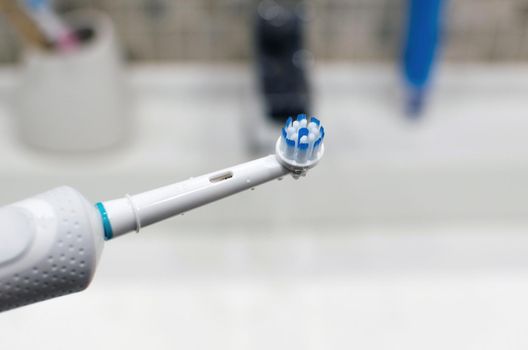 Rechargeable, electric toothbrush, close-up. Against the backdrop of a bathroom in white.