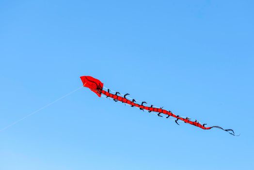 Flying kite. Colorful kite flying in the wind in the blue sky among the clouds. Long serpent in the form of a red dragon