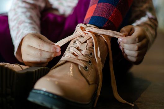 the girl ties the laces on her shoes, in red tights