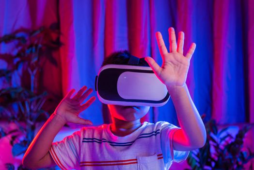 Asian little kid boy wearing virtual reality goggles experiencing reality