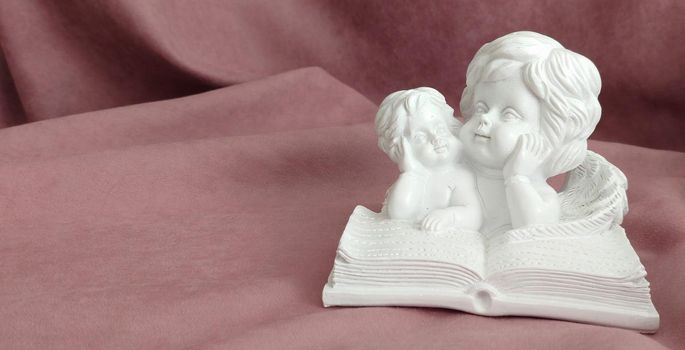 A statuette of little angels reading a book