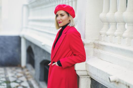 Trendy woman in beret near fence outdoors