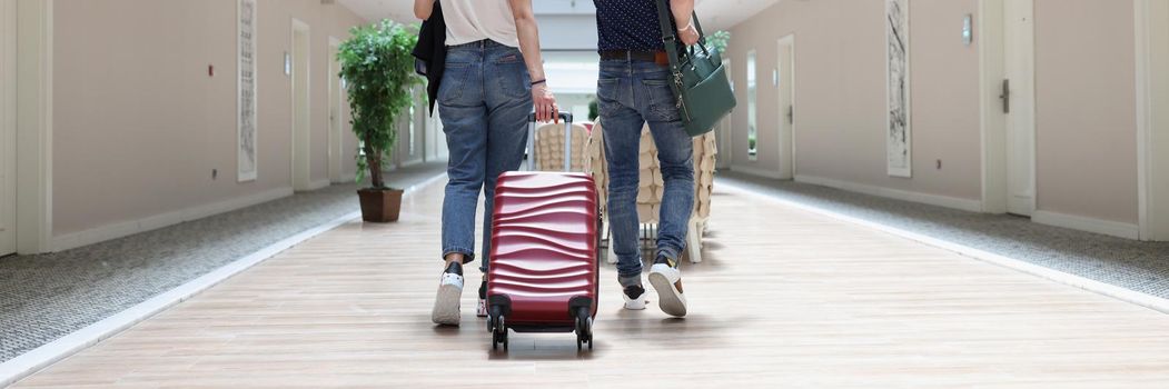 Couple walking with luggage along the hotel corridor