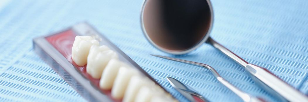 Orthodontist tools and dental bridge on a blue background