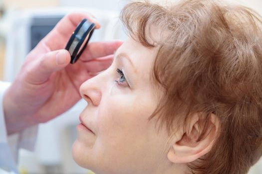 A male ophthalmologist checks the eyesight of an adult woman with a binocular ophthalmoscope