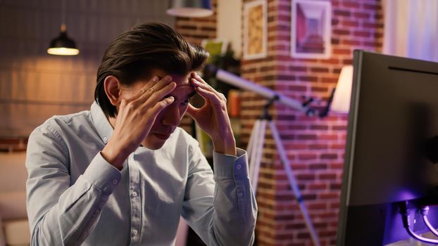 Businessman dealing with headache and migraine at remote job