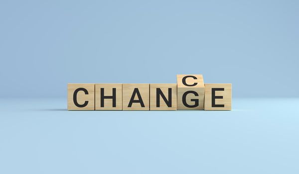 Change for chance concept. Wooden cube block flip over word change to chance on blue studio background.
