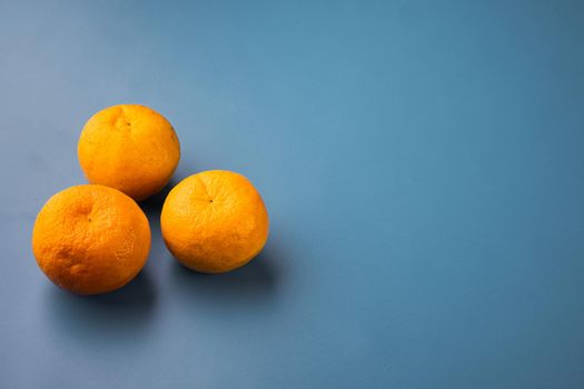 Fresh organic orange fruit, on blue textured summer background, with copy space for text