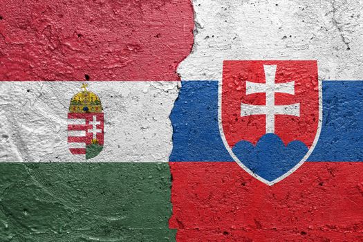 Hungary and Slovakia - Cracked concrete wall painted with a Hungarian flag on the left and a Slovakian flag on the right stock photo