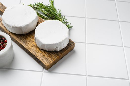 Creamy Brie cheese on white ceramic squared tile table background, with copy space for text