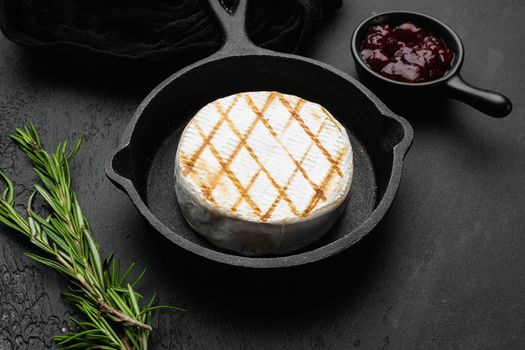 Baked Camembert cheese on black dark stone table background