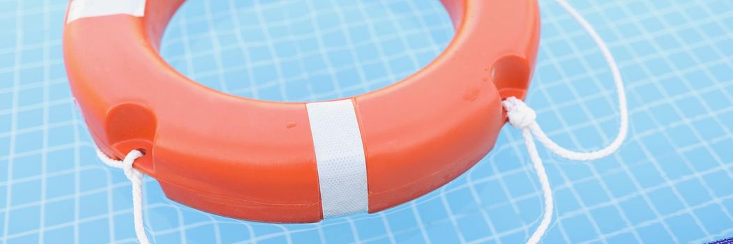 Red lifebuoy in the pool, blue clear water, close-up
