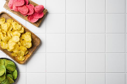 Variation different potato chips on white ceramic squared tile table background, top view flat lay, with copy space for text