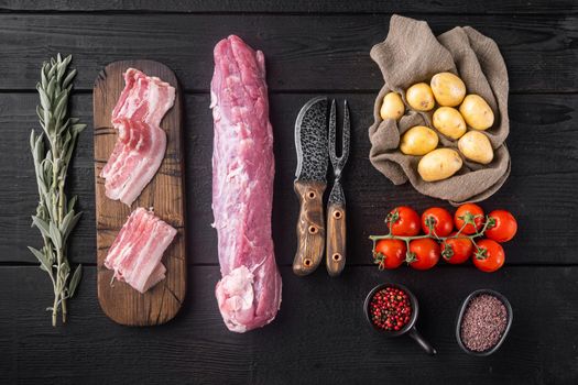 Raw pork tenderloin with ingredients and herbs , on black wooden table background, top view flat lay