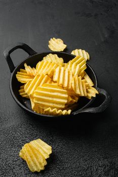 Wavy Lightly Salted Potato Chips on black dark stone table background