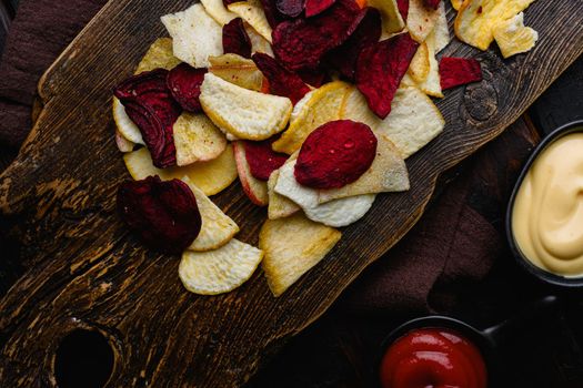 Root Vegetable Crisps, on black wooden table background, top view flat lay