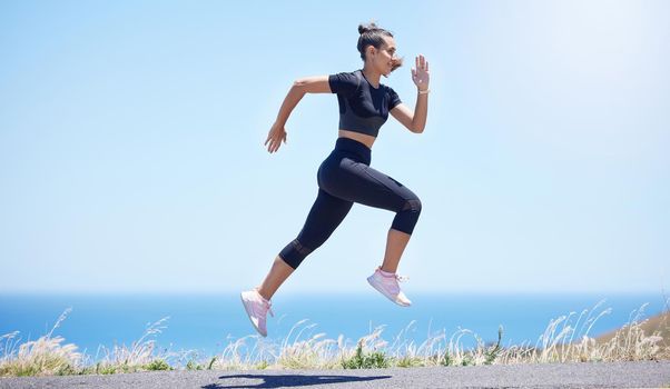 Young fit mixed race female running outside during a her daily exercise routine while jumping in mid air
