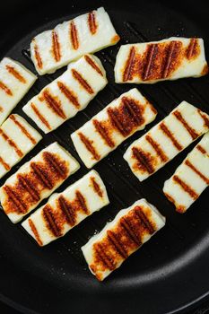 Grilling Halloumi Cheese, on old dark rustic table background, top view flat lay