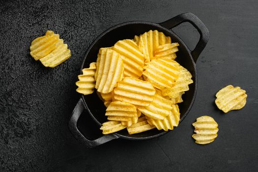 Wavy Ranch Flavored Potato Chips on black dark stone table background, top view flat lay