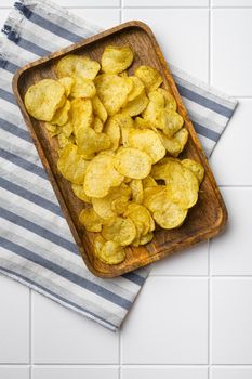Root Classic potato chips on white ceramic squared tile table background, top view flat lay