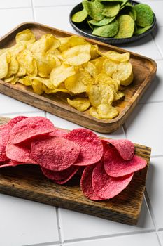 Potato chips pink colored on white ceramic squared tile table background