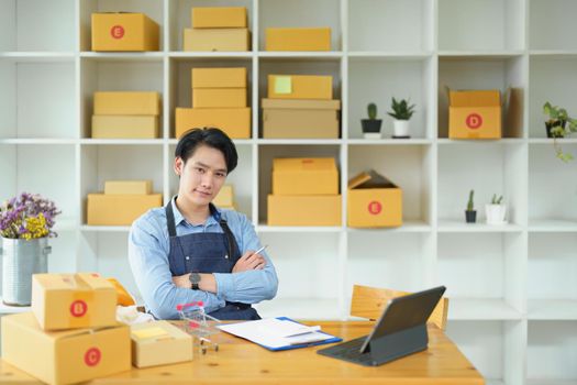 Picture of a small start-up and SME owner, an Asian male entrepreneur checking orders to organize products before packing them into inner boxes for customers