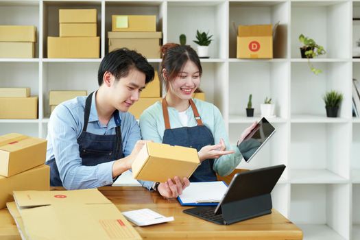 Portrait of a small start-up and SME owner, an Asian male and female entrepreneur checking orders and packing for customers, self-employed, freelance, online selling