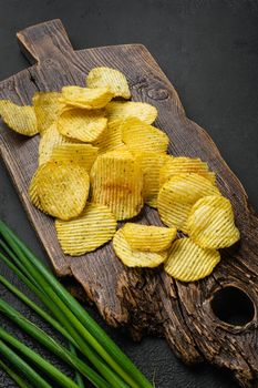 Wavy Potato Chips on black dark stone table background