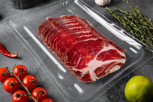 Vacuum packed cured coppa ham , on gray stone table background